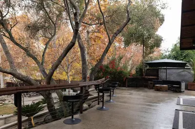 a patio with chairs and a grill and trees at River Magic - Riverfront Family Fun & Lux Design in Three Rivers