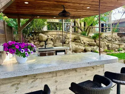 a patio with chairs and a table and flowers at River Magic - Riverfront Family Fun & Lux Design in Three Rivers