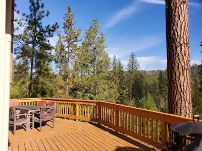 a wooden deck with a picnic table and a tree at Serenity View, Peaceful & Cheerful 3BD Cabin in Groveland