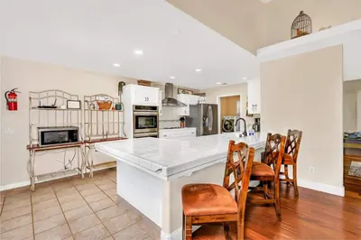 a kitchen with a large white counter and chairs at Awesome Views Game Room Hot Tub and More in Oakhurst