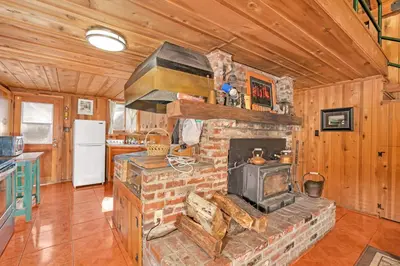 a living room with a stone fireplace in a cabin at Rustic Knotty Pine - Old Cabin Vibes in Shaver Lake