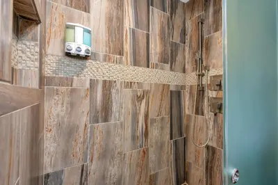 a bathroom with a wooden wall with a shower stall at Immersed in Nature Manzanita Cabin with Hot Tub in Oakhurst