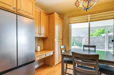 a kitchen with a table and a refrigerator at 5 Mi to Dtwn Modesto Family Home with Patio! in Modesto