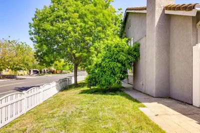 a tree next to a white fence next to a street at 5 Mi to Dtwn Modesto Family Home with Patio! in Modesto