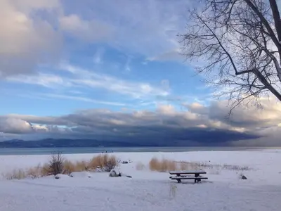 a bench sitting in the snow next to a lake at Hyphen 5-bedrooms rental, private beach, filtered view in Tahoe City