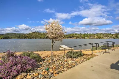 a park bench next to a lake with a tree at Yosemite Home Base Community Perks and Lake Access! in Groveland