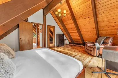 an attic bedroom with a bed and a chair at Spacious Truckee Retreat with Fireplace & Deck in Truckee