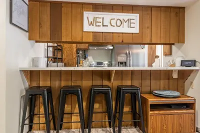 a kitchen with black stools at a counter at Ground Level, Sunshine Village #171- 2 bed/2 bath, Sleeps 6. Steps from Free Town Shuttle in Mammoth Lakes