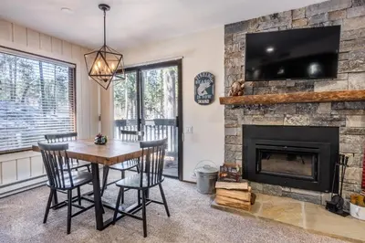 a living room with a fireplace and a table and chairs at Ground Level, Sunshine Village #171- 2 bed/2 bath, Sleeps 6. Steps from Free Town Shuttle in Mammoth Lakes