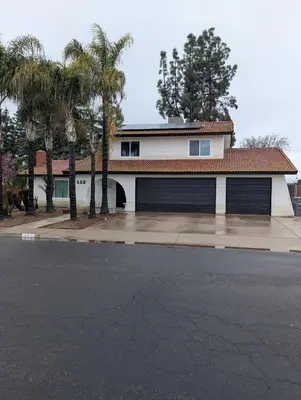 a house with two garage doors and palm trees at Welcome to Lilith's House! in Clovis