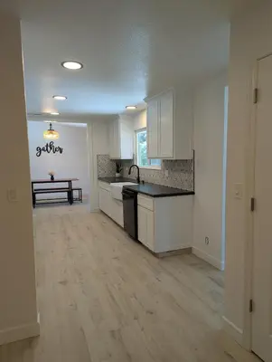 a kitchen with white cabinets and a wooden floor at Welcome to Lilith's House! in Clovis