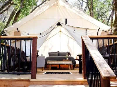a tent with a bed and a table on a deck at Secluded Safari Tent Situated in Rural Western El Dorado County Overlooking Majestic Folsom Lake, Northern California in Pilot Hill