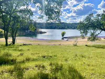 a view of a lake in a field with trees at Secluded Safari Tent Situated in Rural Western El Dorado County Overlooking Majestic Folsom Lake, Northern California in Pilot Hill