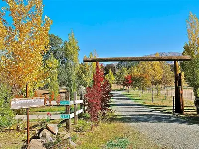 a trail with a wooden gate and autumn leaves at Quiet Cottage Rental for Two in Horse Country near Yosemite National Park Gateway, California in Catheys Valley