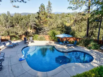 a swimming pool in the middle of a yard at Spacious Mountain View Home - Pool, Spa & Game Rm in Oakhurst