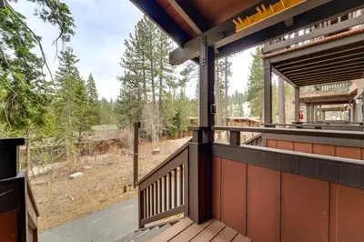 an outdoor deck with a view of a forest at Hike, Sled and Ski! Cozy Tahoe City Condo with Hot Tub in Tahoe City