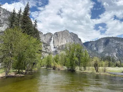 a river with a waterfall in front of a mountain at The Mountains are Calling - Private, Guesthouse Retreat near Yosemite in Ahwahnee