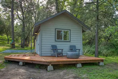 a tiny house with two chairs on a wooden deck at The Mountains are Calling - Private, Guesthouse Retreat near Yosemite in Ahwahnee