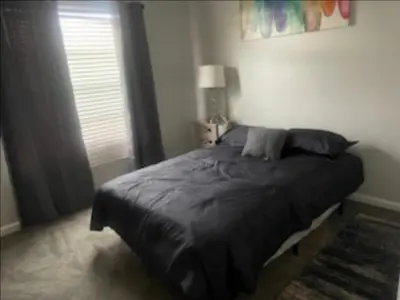 a bedroom with a black bed with a lamp and a window at Spacious 4 bedroom house! in Stockton