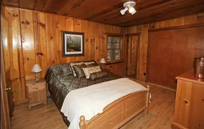 a bedroom with a bed in a room with wooden walls at Spacious Riverfront Cabin Rental Perfect for Large Groups near Sonora, California in Strawberry