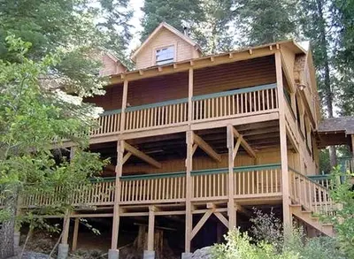 a large wooden house with a large balcony at Spacious Riverfront Cabin Rental Perfect for Large Groups near Sonora, California in Strawberry