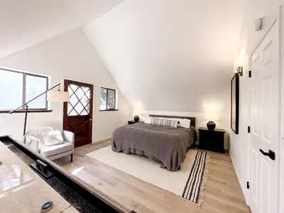 a white bedroom with a bed and a chair at Fabulous Glamping Spot in Truckee, California: Charming Cabin near Lake Donner in Truckee