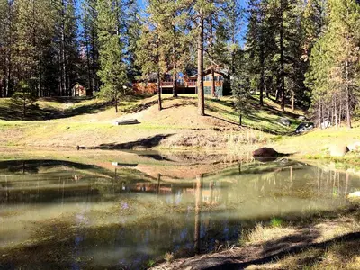 a small pond with a house in the background at Gorgeous Vacation Rental with Hot Tub near Yosemite National Park, California in Mariposa