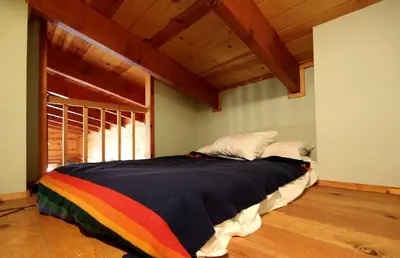 a bed with a rainbow blanket on it in a room at Cozy Log Cabin near Yosemite National Park in California in Mariposa