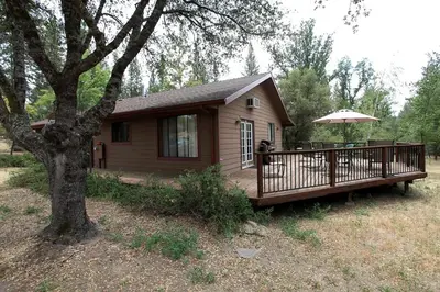 a small house with a deck with an umbrella at Family-Friendly Cabin near Yosemite National Park in California in Mariposa
