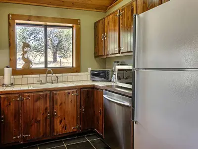 a kitchen with wooden cabinets and a stainless steel refrigerator at Family-Friendly Cabin near Yosemite National Park in California in Mariposa