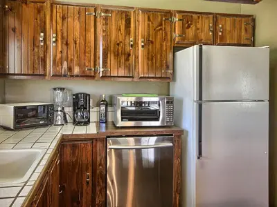 a kitchen with a stainless steel refrigerator and wooden cabinets at Family-Friendly Cabin near Yosemite National Park in California in Mariposa