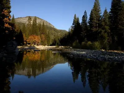 a river with trees and a mountain in the background at Cozy Riverside Cabin Rental with Easy Access to Chilnualna Falls in California in Wawona