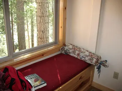 a bench in a room with a window and a book at Exceptional Riverside Cabin Rental in the Trees near Pinecrest Lake, California in Strawberry