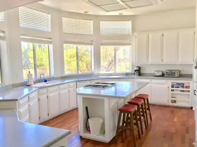 a large kitchen with white cabinets and a island with stools at 3 B 2 BA home in a Serene, quiet cul de sac in Lone Pine