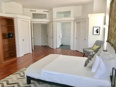 a white bedroom with a large bed and a chair at 3 B 2 BA home in a Serene, quiet cul de sac in Lone Pine