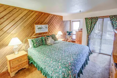 a bedroom with a bed and a wooden wall at Aspen Creek #119 Shared Pool Hot Tub & BBQ in Mammoth Lakes