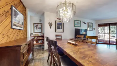 a dining room with a large wooden table and a chandelier at Aspen Creek #215 Hot Tubs Near Golf & Hiking in Mammoth Lakes