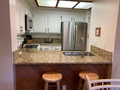 a kitchen with white cabinets and a stainless steel refrigerator at Aspen Creek #226 Year-Round Activities in Mammoth Lakes