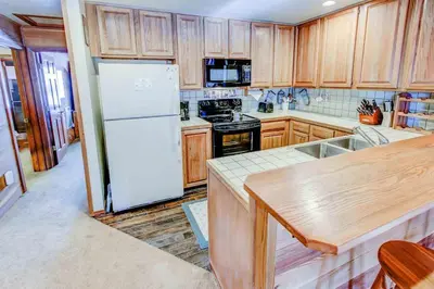 a kitchen with a white refrigerator and wooden cabinets at Canyon Ski & Racquet #1 Near Hike & Bike Trails in Mammoth Lakes