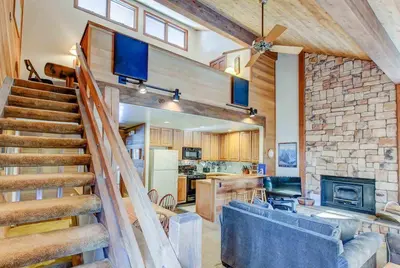 a living room with a staircase leading to a kitchen at Canyon Ski & Racquet #1 Near Hike & Bike Trails in Mammoth Lakes