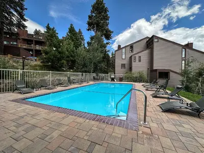 a swimming pool with lounge chairs around it at Canyon Ski Gateway Condo for 4 in Mammoth Lakes