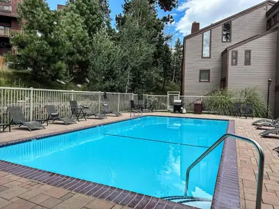 a large blue swimming pool with chairs around it at Canyon Ski Gateway Condo for 4 in Mammoth Lakes