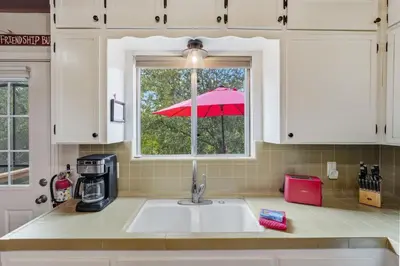 a kitchen with a sink and a window with an umbrella at Fire Escape Cabin-Southern Yosemite in Oakhurst