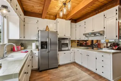 a kitchen with white cabinets and a stainless steel refrigerator at Fire Escape Cabin-Southern Yosemite in Oakhurst