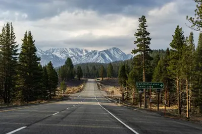 an empty road with snow capped mountains in the distance at Sierra Manors In the Heart of Mammoth in Mammoth Lakes