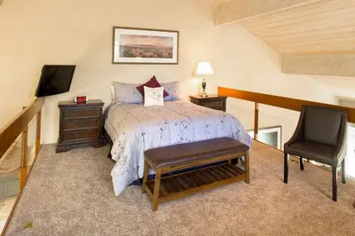 a bedroom with a bed and a tv and a chair at Snowcreek #566 Near Golf & Shuttle in Mammoth Lakes