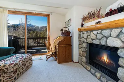 a living room with a stone fireplace with a view at SnowCreek #936 Shared Pool & Hot Tub in Mammoth Lakes