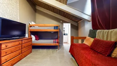 a bedroom with a bunk bed and a tv and a couch at Chamonix #70 Near Yearly Outdoor Activities in Mammoth Lakes