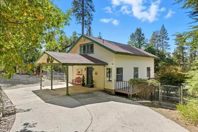 a small yellow house with a porch at Bearfoot Cabin 15 Min to Yosemite Gate! in Oakhurst