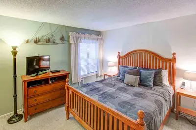 a bedroom with a wooden bed and a television at Fireside Pool Access Hot Tub & More in Mammoth Lakes